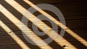 Casts diagonal shadows across a wooden surface emphasizing the
