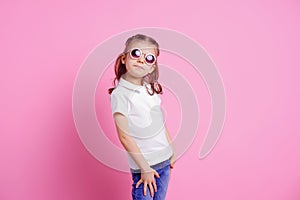 Casual 7 y.o. female in pink round sunglasses isolated on pink background