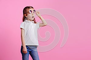 Casual 7 y.o. female in pink round sunglasses isolated on pink background