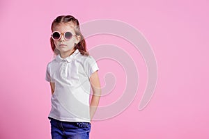 Casual 7 y.o. female in pink round sunglasses isolated on pink background