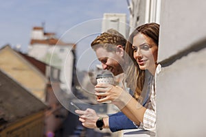 Casual business colleagues looking through office window while taking coffee break