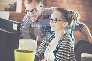 Casual business couple using computer in the office