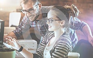 Casual business couple using computer in the office. Two colleagues working together on an innovative product design