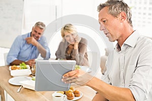 Casual business people looking at tablet while lunch