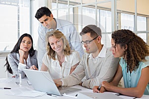 Casual business team having a meeting using laptop