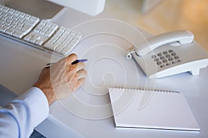 Casual businessman at desk with notepad and telephone