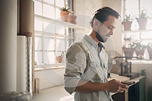 Casual businessman in his studio looking at phone