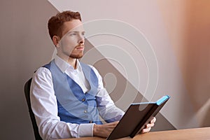 Casual businessman with pen in writing on paper notebook in office in shirt