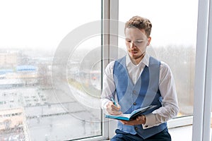 Casual businessman with pen in writing on paper notebook in office in shirt