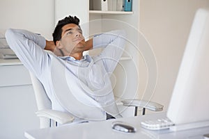 Casual businessman relaxing at desk leaning back