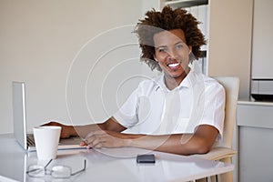 Casual businessman smiling at camera at his desk