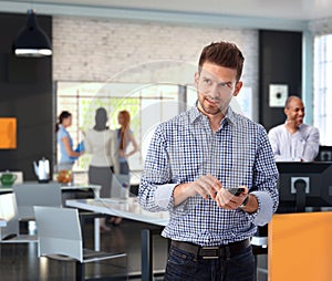 Casual businessman using mobile phone at office