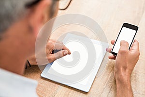 Casual businessman using smartphone and tablet