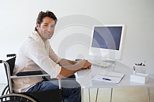 Casual businessman in wheelchair working at his desk