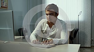 Casual businessman working in light office, sitting at desk, typing on keyboard