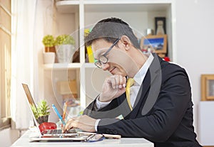 Casual businessman working in office, sitting at desk, typing on keyboard, looking at computer screen