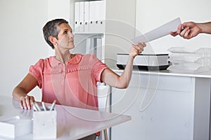 Casual businesswoman handing document to colleague