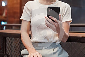 Casual Businesswoman holding and using smartphone for sms messages, young woman typing touchscreen mobile phone in cafe or modern