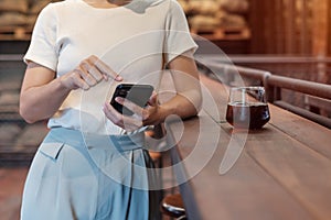 Casual Businesswoman holding and using smartphone for sms messages, young woman typing touchscreen mobile phone in coffee cafe or