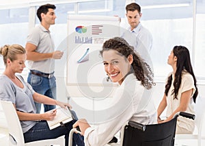 Casual businesswoman in wheelchair smiling at camera during meeting