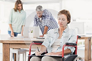 Casual businesswoman in wheelchair taking notes