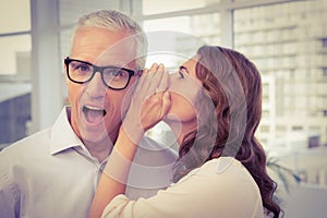 Casual businesswoman whispering secret to her colleague