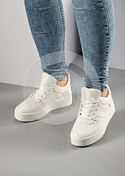 Casual comfortable white sneakers on female model in studio.