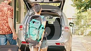 Casual couple putting voyage baggage inside vehicle trunk