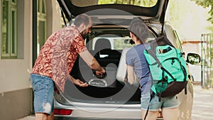 Casual couple putting voyage baggage inside vehicle trunk