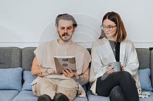 Casual couple relaxing on sofa with tablet