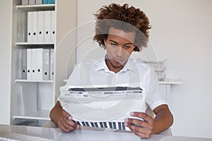 Casual focused businessman reading newspaper at desk