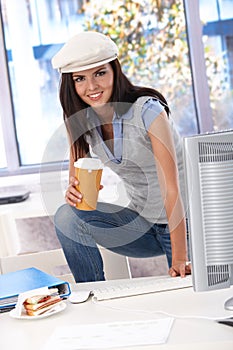 Casual girl having coffee-break at desk