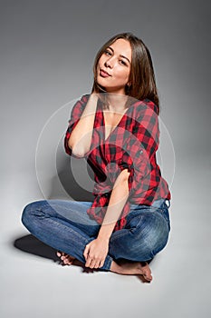 Casual girl sitting barefooted at floor smiling at camera