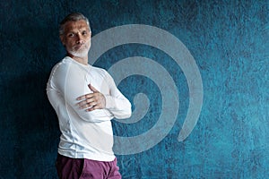 Casual Grey-haired Mature handsome man portrait over dark blue wall background.