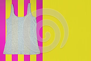 Gray sleeveless female casual tank top on bright striped yellow and pink background. Copyspace. Sport, fitness aparrel. Basic look photo