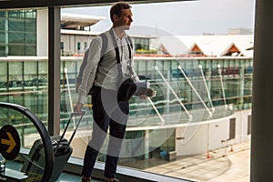 Casual male passenger carrying the hand luggage bag, walking the airplane boarding corridor.