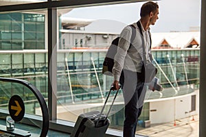 Casual male passenger carrying the hand luggage bag, walking the airplane boarding corridor.