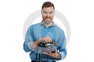 Casual man with blue shirt holding a black old telephone