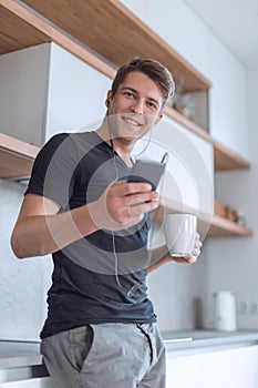 Casual man with a Cup of coffee standing in the kitchen