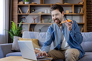 Casual man enjoying pizza while working on laptop at home