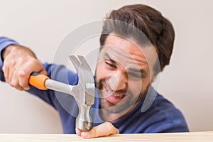 Casual man hammering his finger by accident