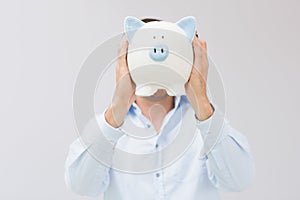 Casual man holding piggy bank in front of his face