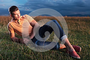 Casual man looks away while laying in grass