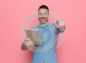 Casual man pointing forward, writing a message on his tablet