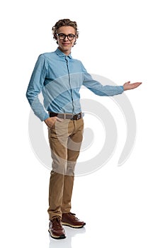 Casual man presenting something to side with hand in pocket