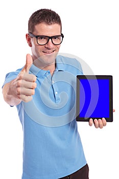 Casual man presents a tablet and shows the thumb up gesture