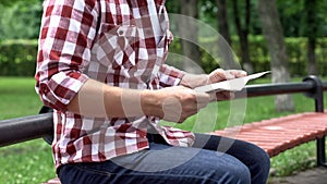 Casual man reading newspaper in park, spending leisure time, carefree weekend