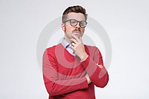 Casual man in red sweater thinking with a hand in his chin