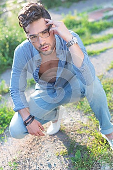 Casual man sits crouched outdoors
