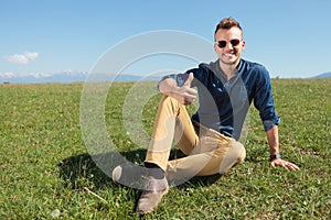 Casual man sits and shows thumb up